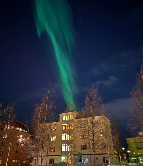 Gult hus i mörker med norrsken i bakgrunden